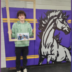 Ayden holding picture frame next to mascot